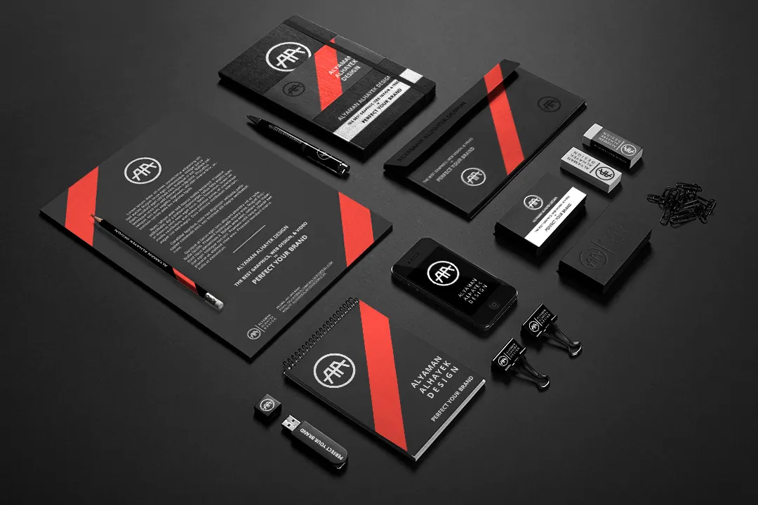 Black business cards, letterhead and envelopes with coral stripes on a dark surface.