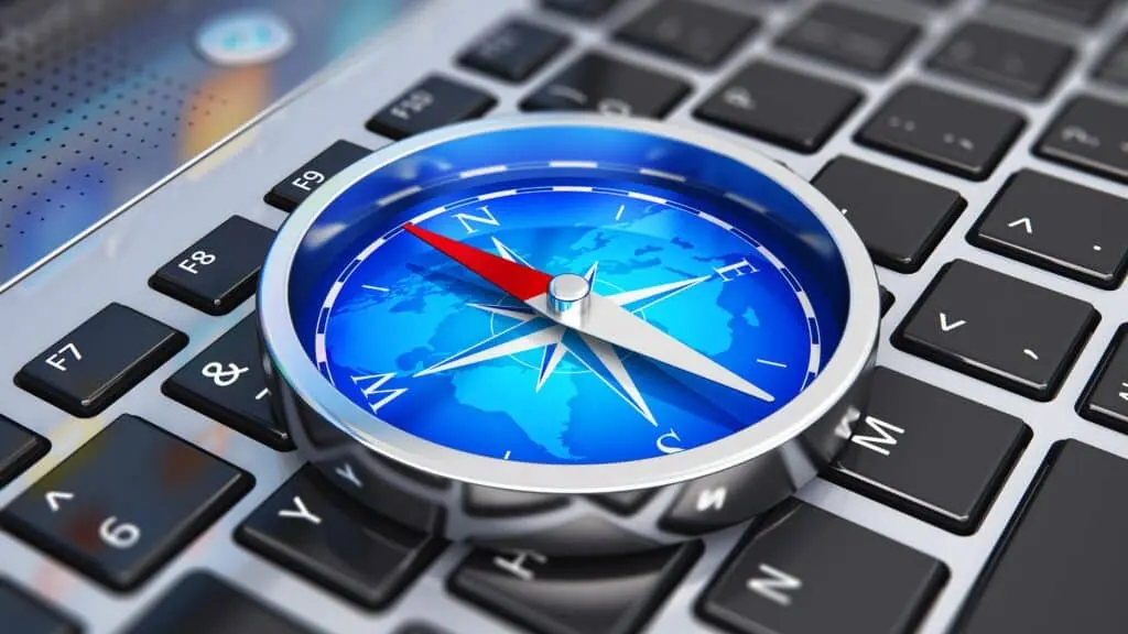 A blue navigation compass resting on a laptop keyboard.