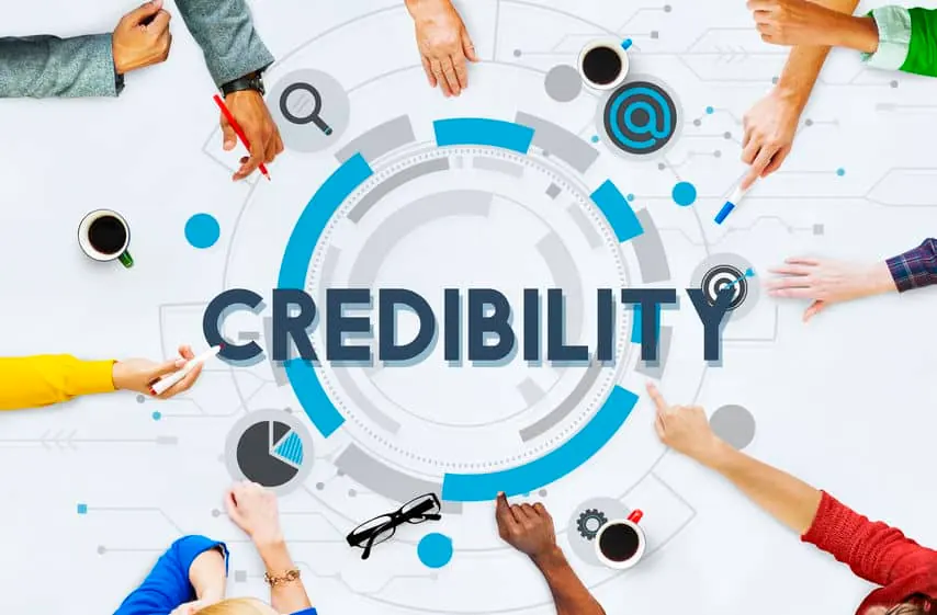 The word Credibility surrounded by icons and hands working at a table.