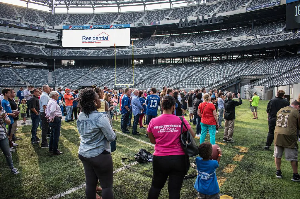 A crowd gathers on a football stadium field during a sponsored event.