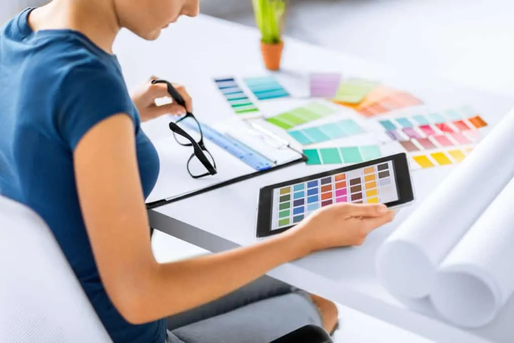 A designer compares colour swatches and a tablet palette at her desk.