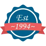 A round blue badge with a red ribbon reading Est 1994.
