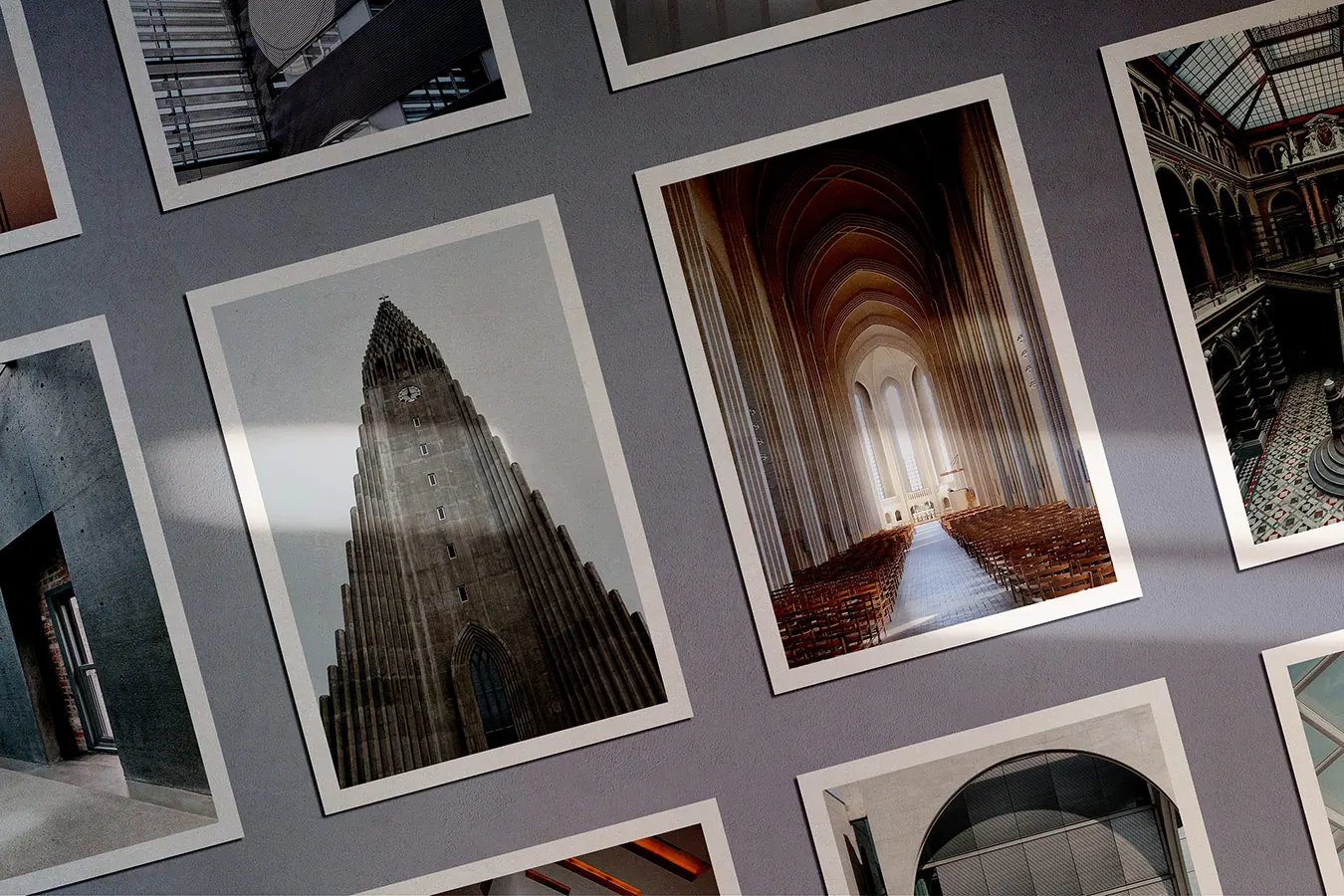 Printed architecture photos of churches and buildings scattered on a grey surface.