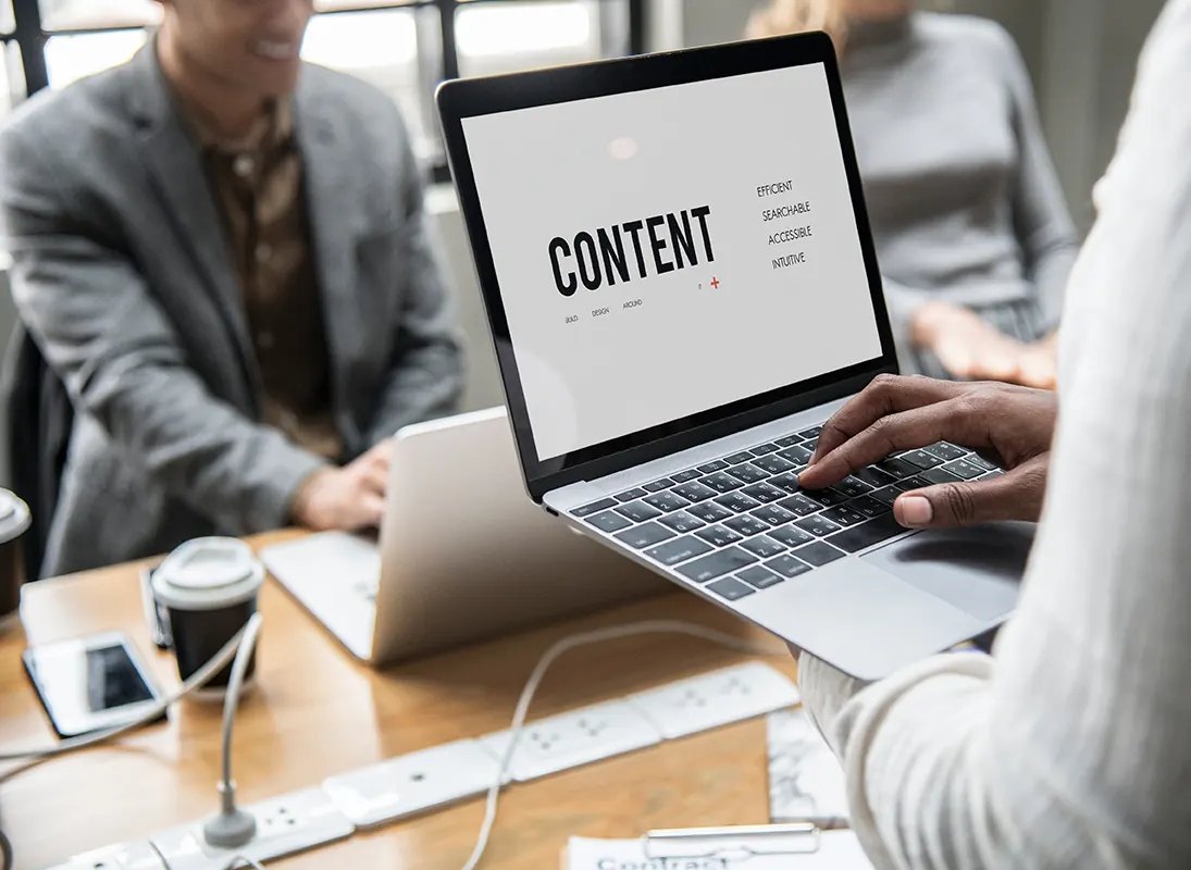 Hands type on a laptop whose screen shows the word Content.