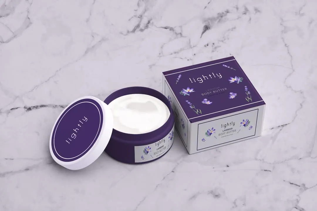 A Lightly body butter jar and purple box on a white marble surface.