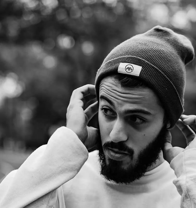 Black and white photo of a bearded man wearing an AA logo beanie.