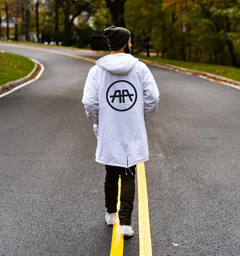 A man walks down a road line wearing a white AA logo jacket.
