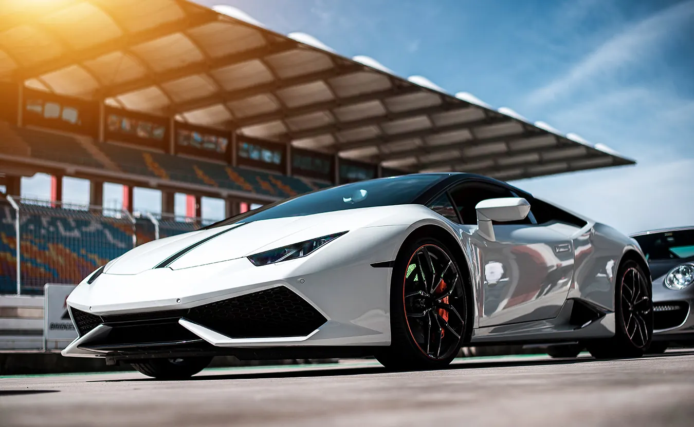 A white sports car parked at a race track in front of the stands.