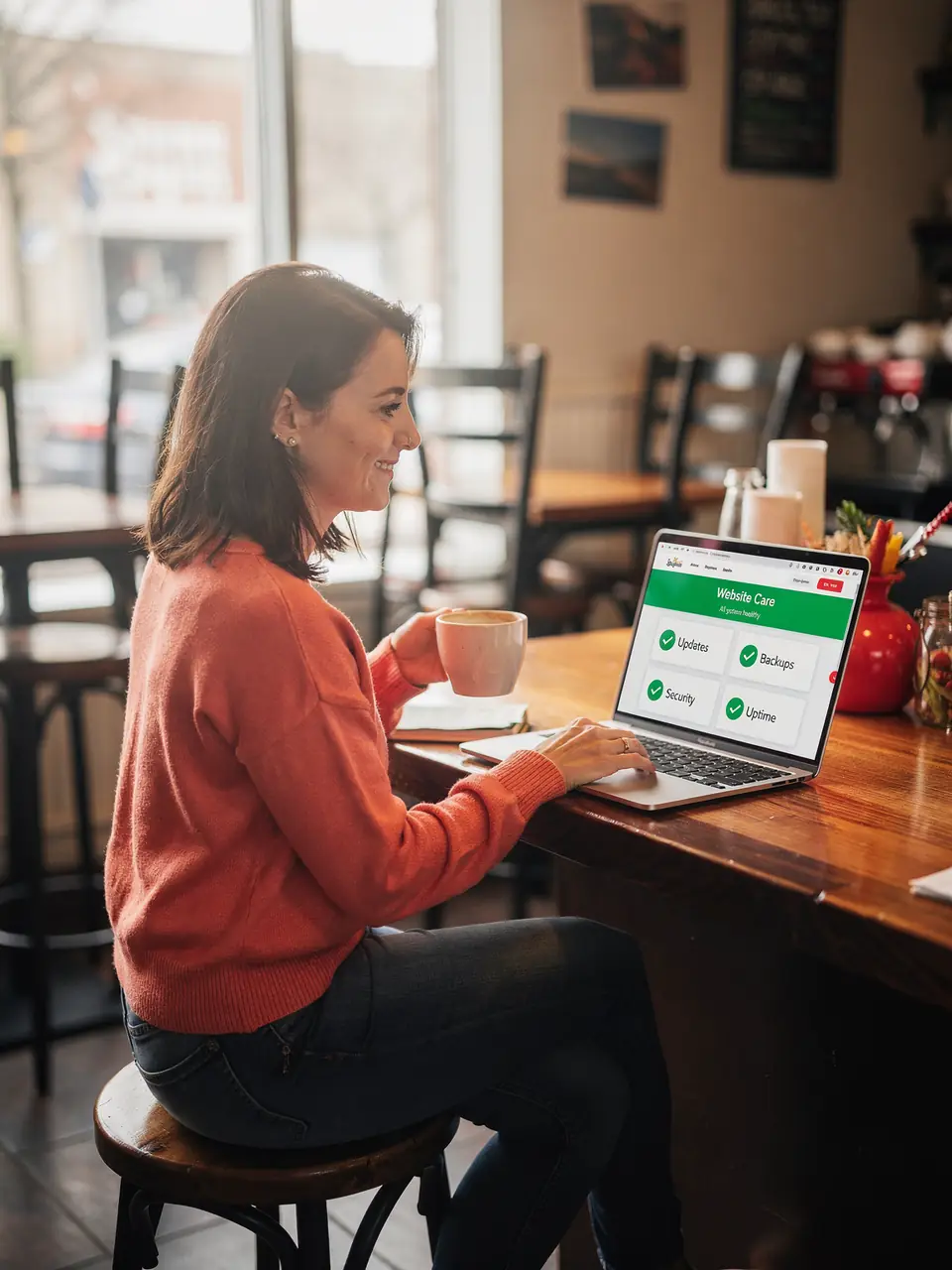 A café owner with coffee checks a website care report on her laptop.