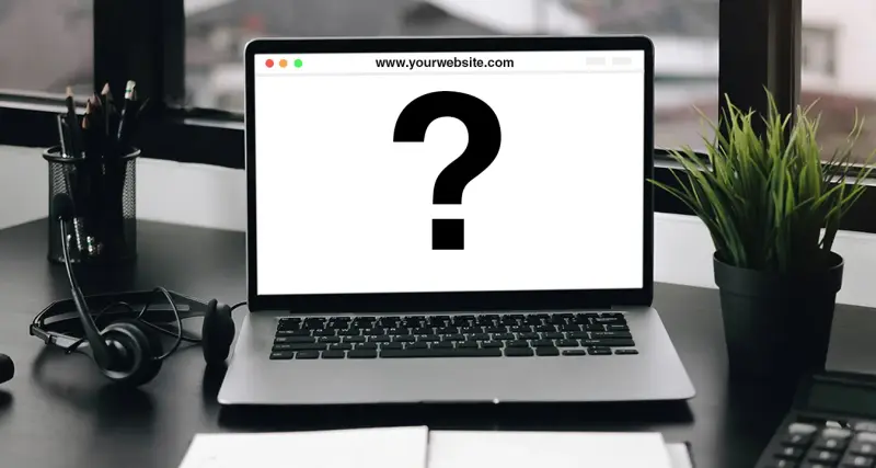 A laptop on a desk shows a website with a large question mark.
